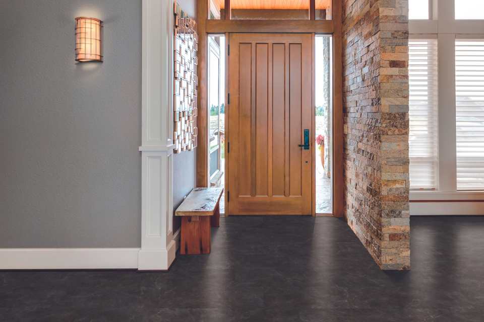 dark stone look luxury vinyl in entryway with brick wall and wood accents